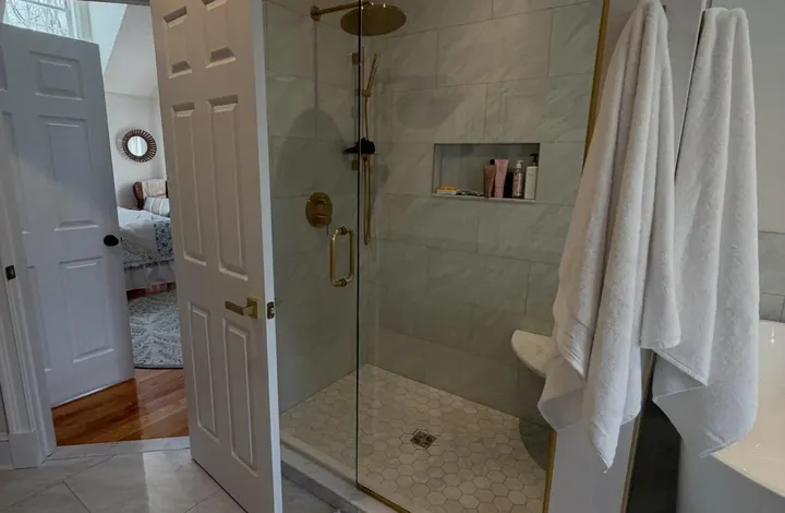Finished bathroom remodel with a marble tile shower and brushed gold fixtures, by River's Edge Home Center