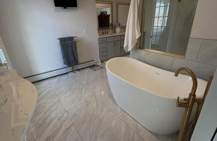 Soaking tub with a wall-mounted television in a remodeled bathroom