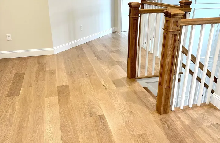 White oak hardwood flooring installed across an upstairs hallway and landing by River's Edge Home Center